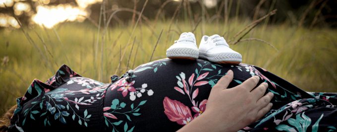 A white baby shoes on a pregnant woman s baby bump in south africa