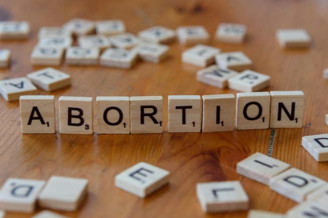 Scrabble tiles spelling abortion on wooden surface